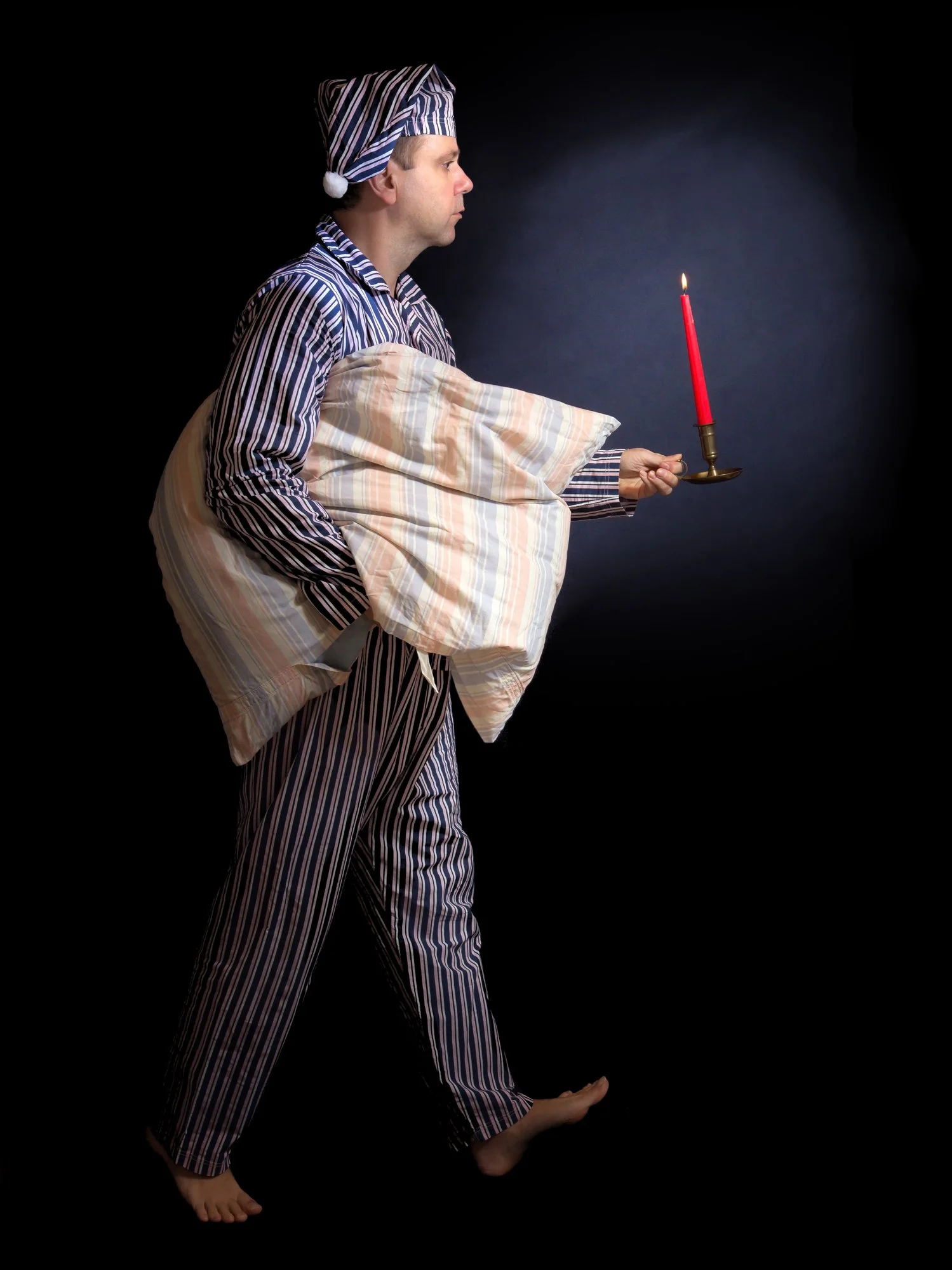 Humorous image of a man in pajamas and nightcap carrying a pillow and candle